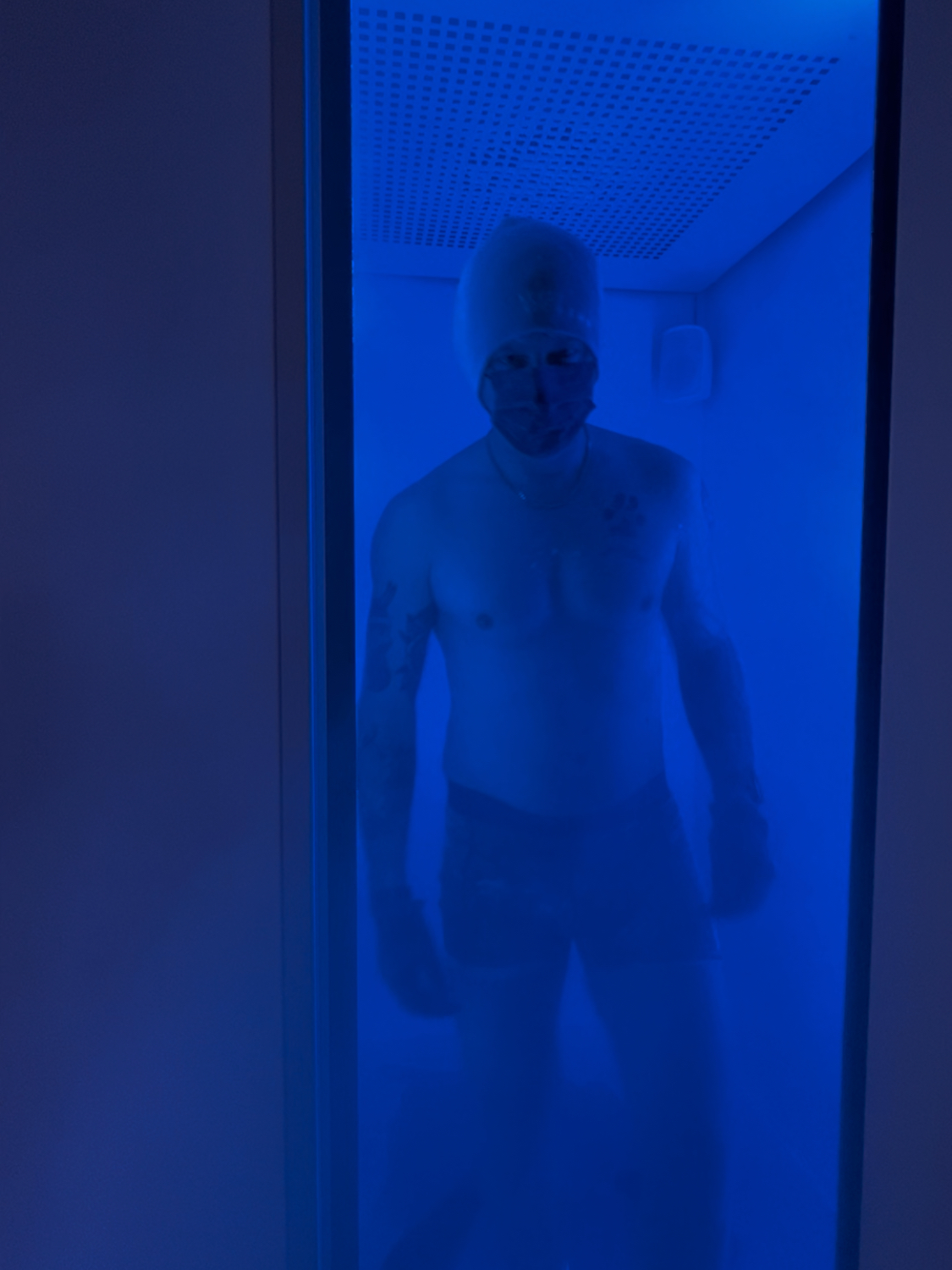 Eiskammer Mann in einer blau beleuchteten Kältekammer mit Mütze und Gesichtsmaske