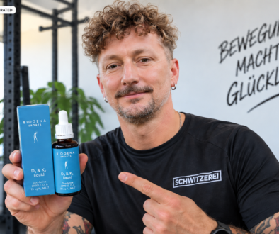 Manfred von der Schwitzerei hält BIOGENA SPORTS D3 & K2 liquid in den Händen und zeigt auf das Produkt im Fitnessstudio.