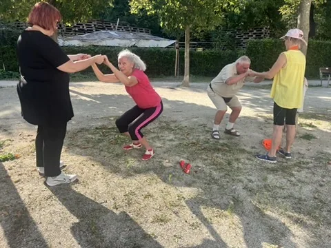 Zwei Paare üben zusammen. Sie halten sich an den Händen. Eine Person geht dabei tief in die Knie.